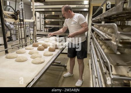 L'illustration montre l'assistant du boulanger avec des pains préparés à l'atelier de la boulangerie 'Bakkerij Bossuyt' à Dilbeek, dans la nuit du vendredi au samedi, vendredi 27 mai 2022. En raison de la crise économique actuelle qui a suivi l'invasion russe en Ukraine qui a succédé à deux années de blocage du virus Corona, les boulangers sont confrontés à la hausse des coûts des ressources de boulangerie telles que la farine de blé et les factures d'énergie élevées. BELGA PHOTO HATIM KAGHAT Banque D'Images