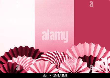 Cadre vibrant avec ventilateurs pliés, cercles sur fond noir, rose et blanc sur fond deux tons. Banque D'Images