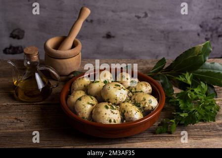 Champignons crus dans un plat de cuisson en argile, assaisonnés et prêts à aller au four. Banque D'Images