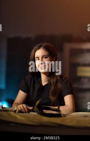 Portrait d'une jeune femme brune dans un uniforme médical noir dans une salle d'examen. Une femme médecin otolaryngologiste tient dans ses mains un dispositif pour Banque D'Images