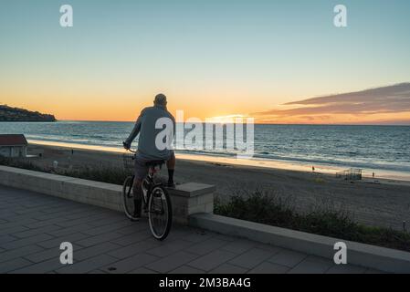 Homme admirant le coucher du soleil assis sur un vélo à Redondo Beach, Californie. Banque D'Images