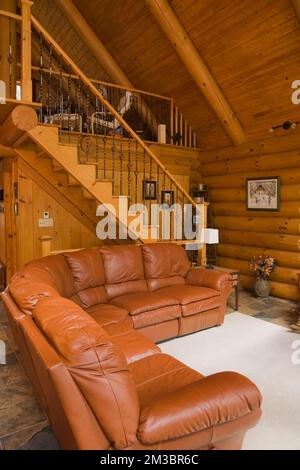 Salon et escalier menant à la chambre principale à l'étage à l'intérieur d'une maison en rondins résidentielle. Banque D'Images