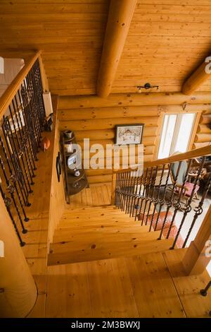 Escalier en bois et balustrade avec balustres en fer forgé menant de la chambre principale à l'étage au salon du rez-de-chaussée à l'intérieur de la cabane en rondins. Banque D'Images