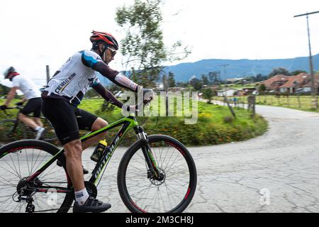 Un homme qui fait du vélo de montagne sur une route asphaltée dans les montagnes de bogota pendant un exercice autorisé en quarantaine du coronavirus. Banque D'Images