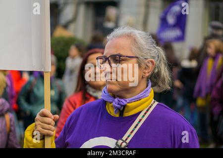 Une vieille femme aux lunettes noires tenant un panneau de protestation lors de 8M marches de la Journée internationale de la femme en revendiquant ses droits Banque D'Images