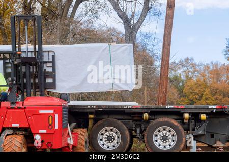 Les chariots élévateurs sont utilisés pour décharger des pièces de matériaux de construction du camion sur le chantier de construction Banque D'Images