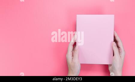 Une boîte rose carrée avec une copie vide espace pour le texte et le dessin en main de la jeune femme sur un fond rose. Couleur de l'année 2023 Viva Magenta. Carte, Banque D'Images