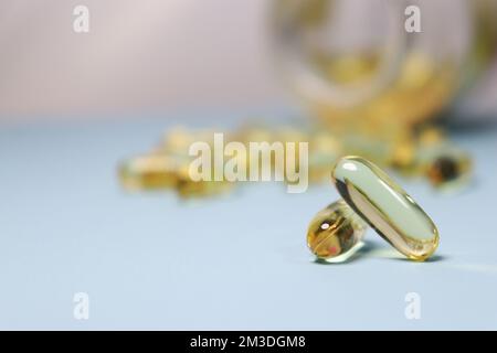 gros plan des capsules d'huile de poisson et de la bouteille sur fond bleu Banque D'Images