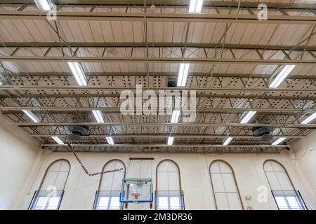 Plafond d'un gymnase américain non-descript avec structures de toit en métal et lampes fluorescentes. Banque D'Images