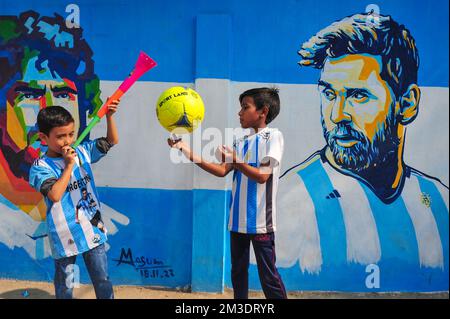 Non exclusif: 14 décembre 2022 à Sylhet, Bangladesh: De jeunes fans argentins célébrant, pose devant une fresque de son héros, Lionel Messi, gagne sur Cro Banque D'Images
