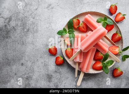 Glaces aux fraises surgelées faites maison et fraises fraîches sur fond de béton. Dessert d'été Banque D'Images