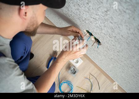 Électricien travaillant en toute sécurité sur les interrupteurs et les prises du système électrique domestique, vue de dessus Banque D'Images