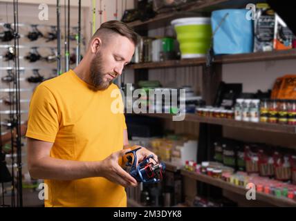 Homme avec tambour tournant dans la boutique de sport, gros plan. Équipement de pêche Banque D'Images
