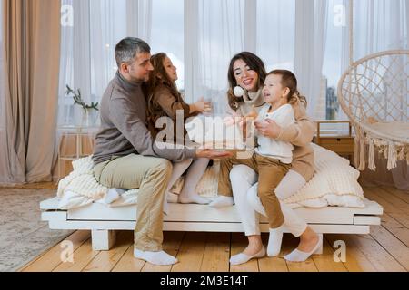 Famille heureuse quand maman et papa passent du temps à la maison avec deux enfants. Les parents jouent dans le lit. Relations dans la famille Banque D'Images