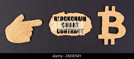 Concept d'entreprise et de technologie. Sur fond noir, des figures en carton du symbole bitcoin et une main pointant vers un signe avec l'inscription - B. Banque D'Images