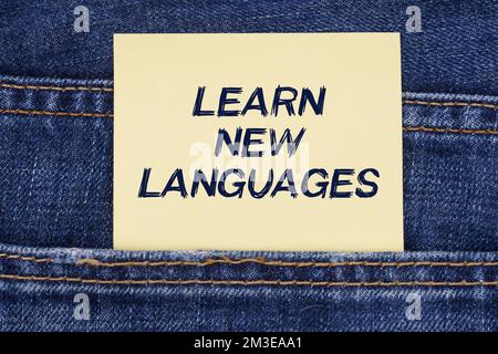 Concept d'économie et d'éducation. Il y a un papier qui colle d'une poche de jeans avec l'inscription - apprendre de nouvelles langues Banque D'Images