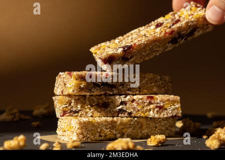 Femme prend le bar énergétique Granola naturel maison. Variété de barres de petit-déjeuner de granola de protéines, avec noix, raisins secs, cerises séchées et chocolat. Nutrition saine alimentation. Collation sans gluten aux céréales Super food Sport Oridge bar Vega dessert concept Banque D'Images