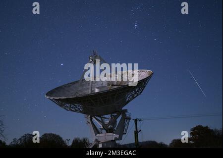 Knockin, Shropshire - 14 décembre 2022 - Un météore filme devant le radiotélescope Knockin dans le Shropshire pendant le pic de la douche de météore des Geminidés de mercredi soir à jeudi matin. Geminids est l'une des douches les plus actives avec jusqu'à 120 par heure. Le radiotélescope Knockin, près d'Oswestry, fait partie d'un réseau géré par l'Observatoire de Jodrell Bank de renommée internationale à Cheshire. Crédit : Scott cm/Alay Live News Banque D'Images