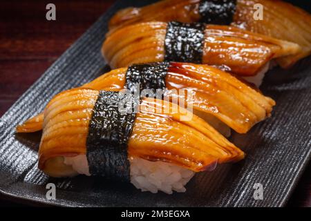 Sushi de style japonais avec poisson à anguille sur une assiette noire, cuisine asiatique, cuisine japonaise traditionnelle. Banque D'Images