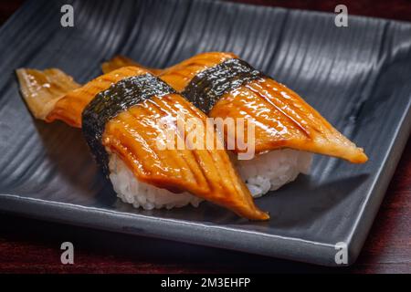 Sushi de style japonais avec poisson à anguille sur une assiette noire, cuisine asiatique, cuisine japonaise traditionnelle. Banque D'Images