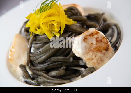 Recette de pâtes Linguine à l'encre de calmar et pétoncles, betterave jaune à chioggia Banque D'Images