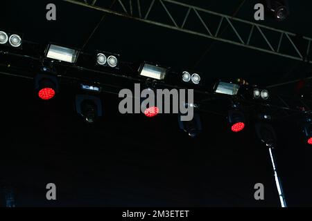 Permet de mettre au point de nombreux spots rouges qui éclairent la scène lors d'un concert avec du brouillard. spots sur une scène de théâtre sur fond noir. Hors foyer. Banque D'Images