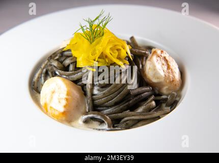 Recette de pâtes Linguine à l'encre de calmar et pétoncles, betterave jaune à chioggia Banque D'Images