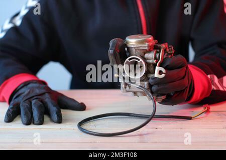 vieux carburateur d'un scooter quatre temps sur la table dans les mains Banque D'Images