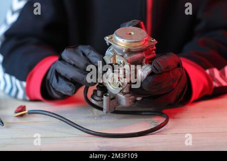 vieux carburateur d'un scooter quatre temps sur la table dans les mains Banque D'Images