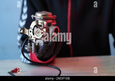 vieux carburateur d'un scooter quatre temps sur la table dans les mains Banque D'Images