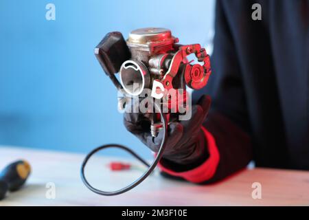 vieux carburateur d'un scooter quatre temps sur la table dans les mains Banque D'Images