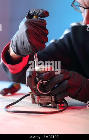 vieux carburateur d'un scooter quatre temps sur la table dans les mains Banque D'Images