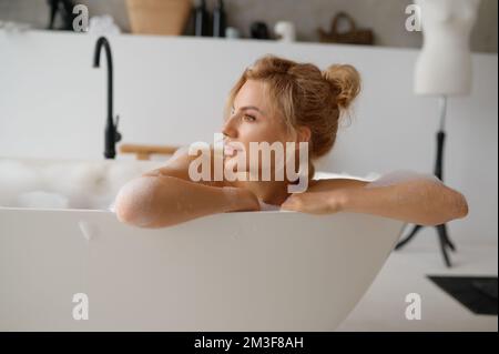 Portrait de la jeune femme pensive prenant bain et regardant loin Banque D'Images
