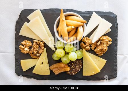 Vue en hauteur sur un plateau de fromages, de craquelins, de noix et de raisins servis sur des cheesboard Banque D'Images