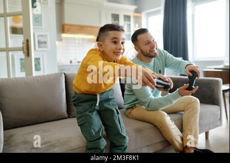 Papa et son fils jouent au jeu vidéo tandis que maman cuisine sur la cuisine Banque D'Images