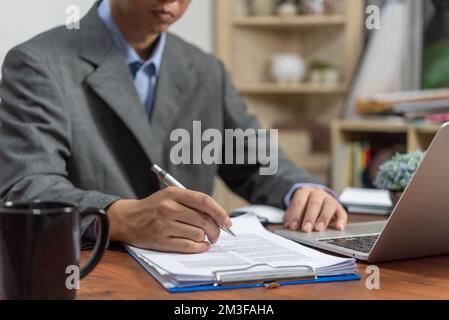 l'homme d'affaires signe les documents avec un stylo faisant la signature sur le bureau. Banque D'Images