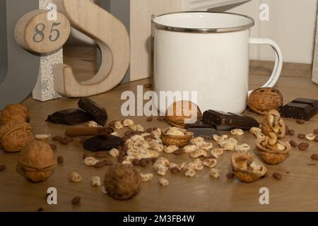 Un gros plan de noix et de chocolats avec une tasse blanche sur une table en bois Banque D'Images