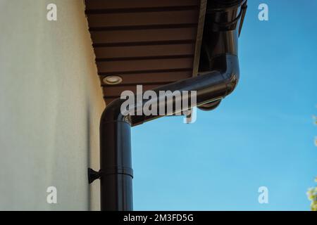 Gouttière marron en PVC fixée à la façade sous le toit Banque D'Images