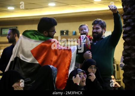 Téhéran, Téhéran, Iran. 14th décembre 2022. Un fan iranien portant un drapeau palestinien (L) alors qu'il assistait au café Nakhlestan du centre-ville de Téhéran pour avoir regardé la demi-finale du match Qatar 2022 de la coupe du monde de la FIFA entre la France et le Maroc à l'écran, 14 décembre 2022. Les fans d'Iran, du Liban, du Yémen, de Syrie et de Palestine se rassemblent au café de Nakhlestan, qui est géré et détenu par l'organisation artistique et médiatique Owj (IRGS) du corps des Gardiens de la révolution islamique, pour soutenir l'équipe nationale marocaine. Après la victoire contre le Portugal au Qatar sur 10 décembre, les Marocains ont porté des drapeaux palestiniens pour montrer leur s Banque D'Images