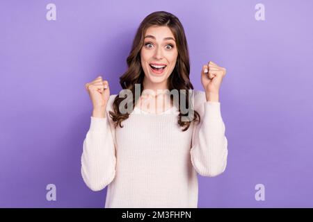 Photo de jeune pleine de joie excitée drôle de fille ondulée cheveux poings vers le haut hooray inattendu devenir millionnaire loterie gagner isolé sur fond violet couleur Banque D'Images