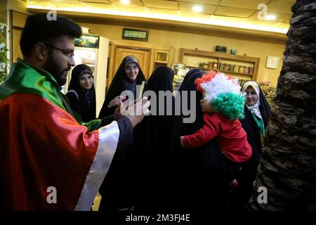 Téhéran, Téhéran, Iran. 14th décembre 2022. Un fan iranien portant un drapeau palestinien (L) alors qu'il assistait au café Nakhlestan du centre-ville de Téhéran pour avoir regardé la demi-finale du match Qatar 2022 de la coupe du monde de la FIFA entre la France et le Maroc à l'écran, 14 décembre 2022. Les fans d'Iran, du Liban, du Yémen, de Syrie et de Palestine se rassemblent au café de Nakhlestan, qui est géré et détenu par l'organisation artistique et médiatique Owj (IRGS) du corps des Gardiens de la révolution islamique, pour soutenir l'équipe nationale marocaine. Après la victoire contre le Portugal au Qatar sur 10 décembre, les Marocains ont porté des drapeaux palestiniens pour montrer leur s Banque D'Images