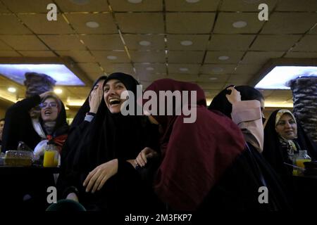 Téhéran, Téhéran, Iran. 15th décembre 2022. Les fans iraniens féminins voilés réagissent alors que l'un d'eux tient une corne tout en regardant la demi-finale du match de la coupe du monde de la FIFA, Qatar 2022 entre la France et le Maroc à l'écran, au café Nakhlestan dans le centre-ville de Téhéran, en Iran, 15 décembre 2022. Les fans d'Iran, du Liban, du Yémen, de Syrie et de Palestine se rassemblent au café de Nakhlestan, qui est géré et détenu par l'organisation artistique et médiatique Owj (IRGS) du corps des Gardiens de la révolution islamique, pour soutenir l'équipe nationale marocaine. Après la victoire contre le Portugal au Qatar sur 10 décembre, les Marocains ont porté des drapeaux palestiniens à Banque D'Images