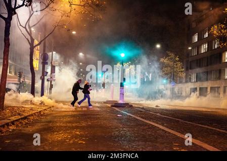 Paris, France. 15th décembre 2022. Deux personnes s'enfuient au milieu de nuages de gaz lacrymogènes lors des émeutes lors des célébrations de la qualification de la France pour la finale de la coupe du monde au Qatar. Émeutes au coeur de Paris après la victoire demi-finale de la France sur le Maroc au Qatar. Plus de 5 000 soldats de la gendarmerie ont été stationnés près de l'Arc de Triomphe à Paris pour disperser les fanatiques qui étaient à l'origine d'incidents violents le soir. (Photo de Ximena Borrazas/SOPA Images/Sipa USA) crédit: SIPA USA/Alay Live News Banque D'Images