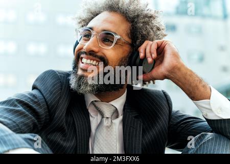 Jeune entrepreneur homme d'affaires à l'écoute de musique et de danse à l'extérieur du bureau. Concept de liberté et de réussite dans les affaires Banque D'Images
