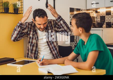 Le père aide son fils à apprendre. Ils font leurs devoirs ensemble. Banque D'Images