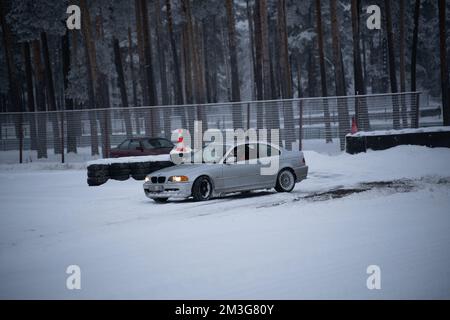 12-12-2022 Riga, Lettonie une voiture garée dans la neige près d'une clôture et des arbres en arrière-plan avec un feu rouge allumé. . Banque D'Images