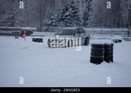 12-12-2022 Riga, Lettonie une voiture blanche garée dans un parking couvert de neige à côté d'un panneau rouge et d'un cône rouge. . Banque D'Images