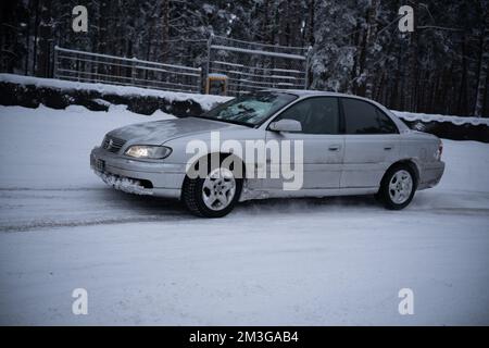 12-12-2022 Riga, Lettonie une voiture est garée dans la neige près d'une clôture et des arbres en arrière-plan. . Banque D'Images