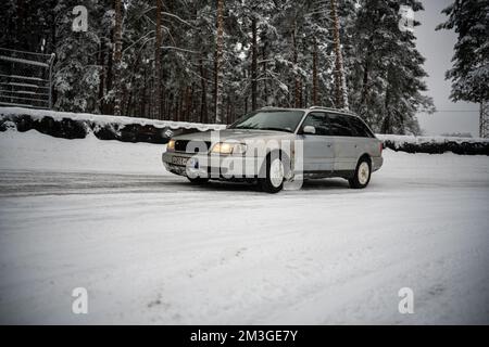 12-12-2022 Riga, Lettonie une voiture est garée dans la neige près d'une forêt d'arbres et d'une clôture avec un snowboard. . Banque D'Images