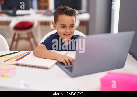 Adorable élève hispanique de tout-petit utilisant un ordinateur portable assis sur une table en classe Banque D'Images